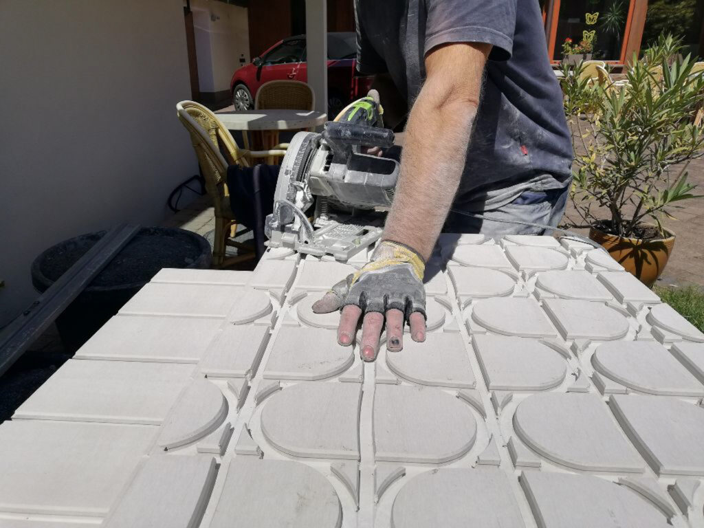 Hand eines Arbeiters auf der Bodenplatte einer Fußbodenheizung