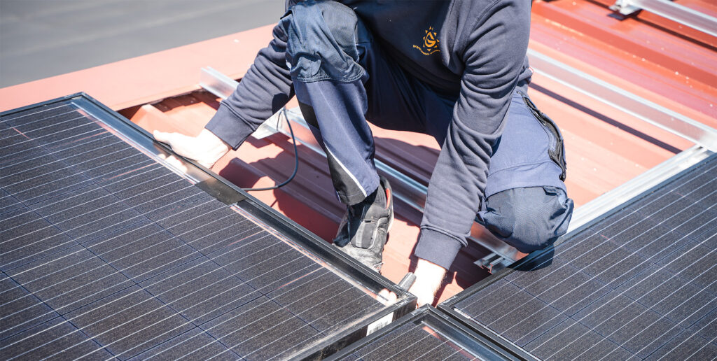 Ein Mitarbeitender von Heizungsbau Günther auf einem Dach beim Installieren einer PV-Anlage.